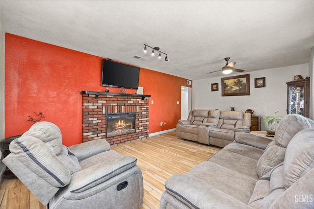 living room with rail lighting, ceiling fan, wood-type flooring, and a fireplace