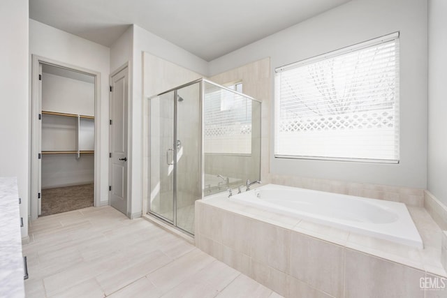 full bathroom featuring a walk in closet, a shower stall, and a garden tub