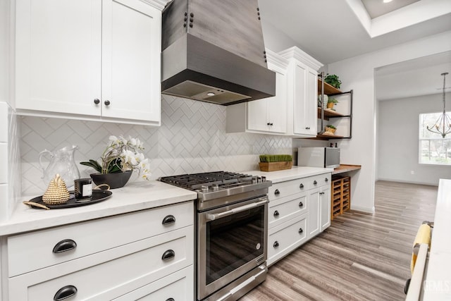 kitchen with custom range hood, white cabinetry, stainless steel stove, light wood finished floors, and light countertops