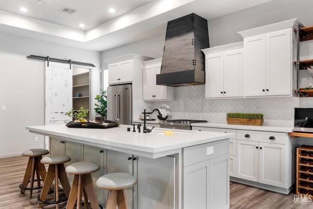 kitchen featuring white cabinetry, stainless steel appliances, light wood-style floors, and premium range hood