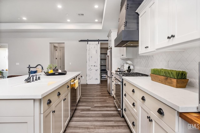 kitchen featuring visible vents, a sink, stainless steel appliances, wall chimney exhaust hood, and light countertops