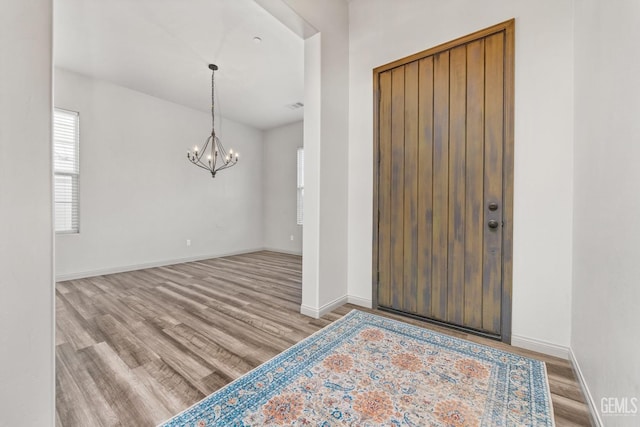 entrance foyer featuring visible vents, baseboards, an inviting chandelier, and wood finished floors