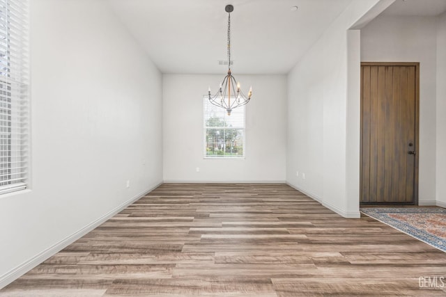 interior space featuring a notable chandelier, wood finished floors, and baseboards