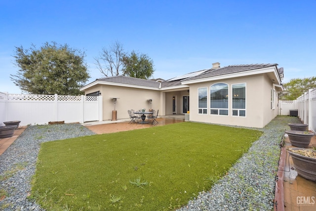 back of house featuring stucco siding, a patio, a lawn, and a fenced backyard