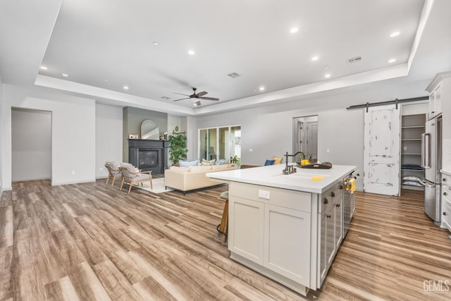 kitchen with high end refrigerator, a raised ceiling, a barn door, and a sink