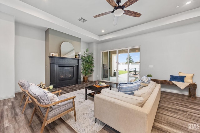 living room with visible vents, baseboards, recessed lighting, wood finished floors, and a glass covered fireplace