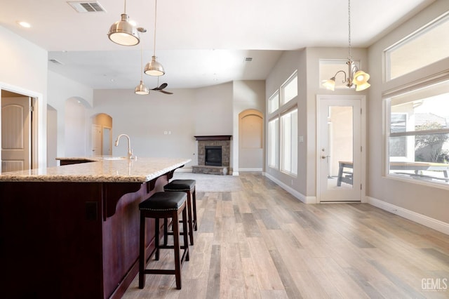 kitchen featuring light wood-style flooring, decorative light fixtures, a fireplace, and visible vents