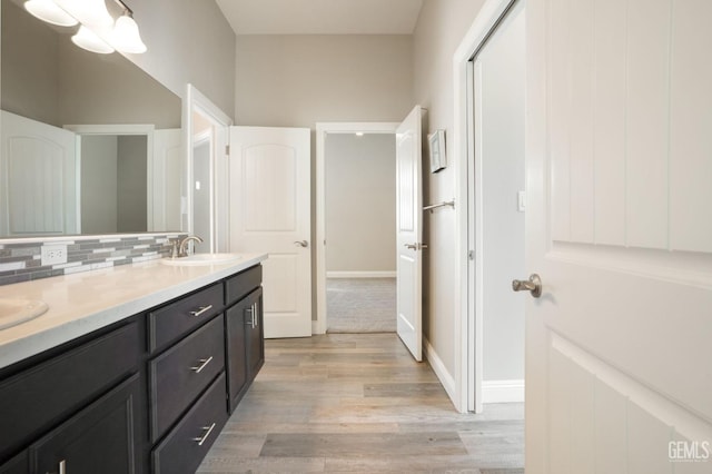 bathroom featuring double vanity, backsplash, wood finished floors, and a sink