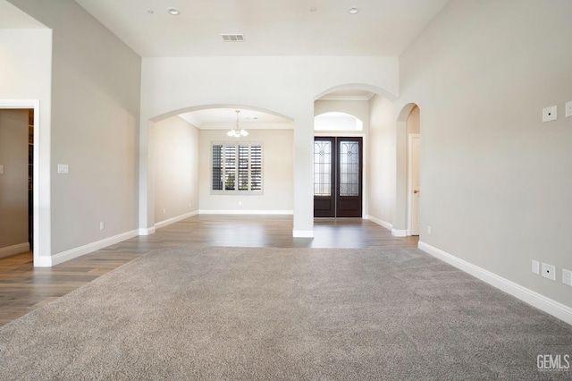 interior space featuring visible vents, a notable chandelier, arched walkways, carpet, and baseboards