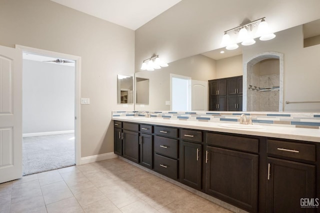 bathroom featuring double vanity, decorative backsplash, baseboards, and a sink