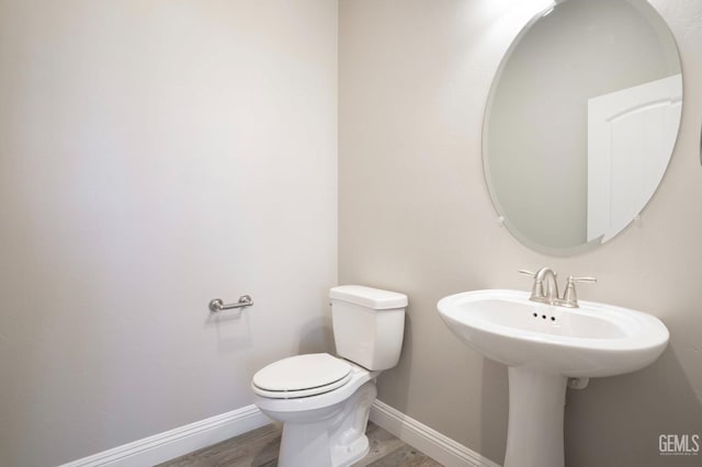 bathroom featuring toilet, baseboards, and wood finished floors