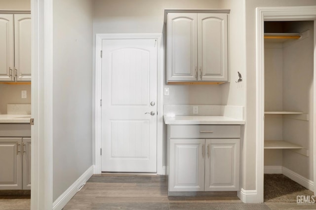 kitchen featuring light countertops, baseboards, and light wood-type flooring