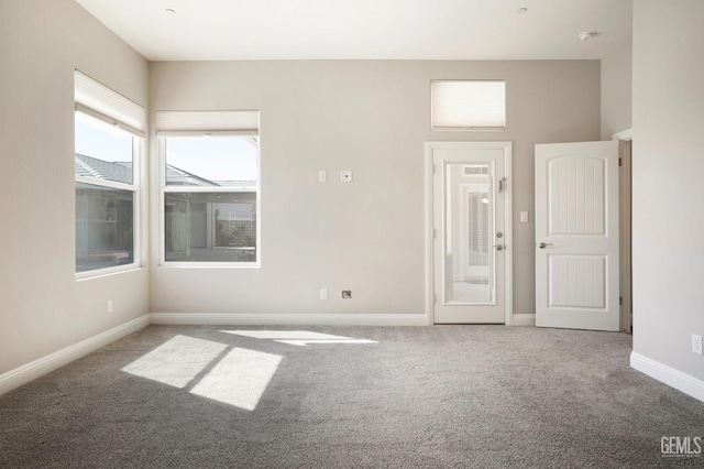 carpeted empty room featuring baseboards