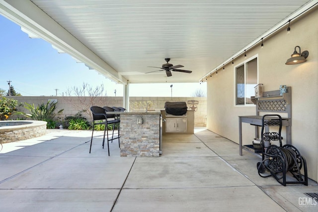 view of patio with exterior kitchen, outdoor wet bar, a fenced backyard, a grill, and a ceiling fan