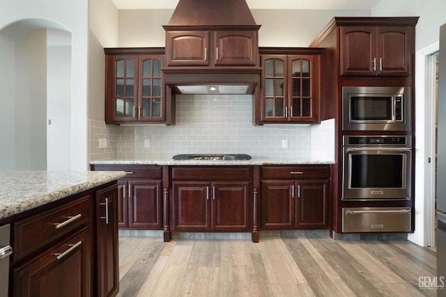 kitchen featuring decorative backsplash, appliances with stainless steel finishes, light wood-type flooring, and a warming drawer