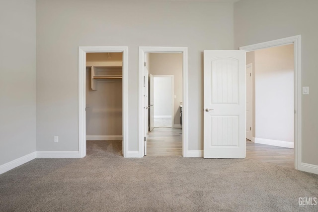 unfurnished bedroom featuring a spacious closet, carpet flooring, a closet, and baseboards