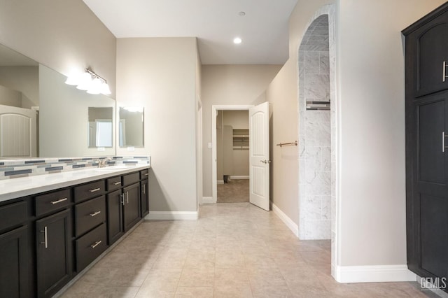 full bathroom featuring a walk in closet, baseboards, tasteful backsplash, and vanity