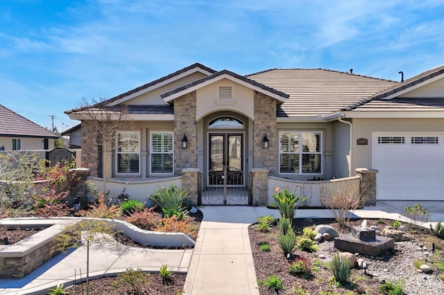 property entrance featuring french doors, stone siding, a garage, and a tiled roof