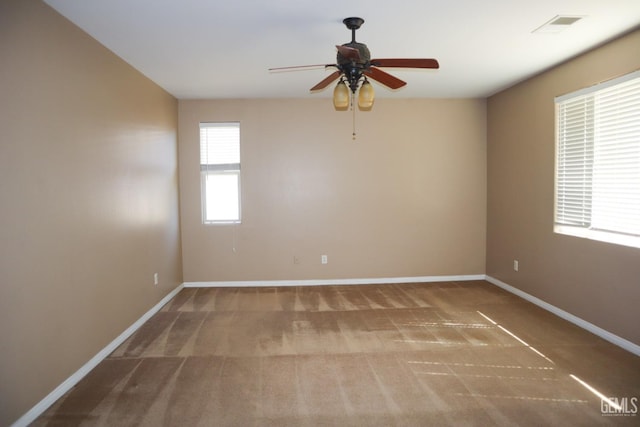 unfurnished room with carpet, visible vents, baseboards, and ceiling fan