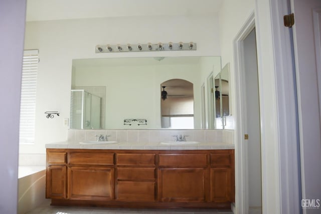 bathroom featuring double vanity, a shower stall, a garden tub, and a sink