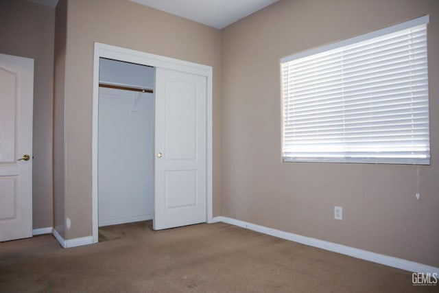 unfurnished bedroom featuring a closet, baseboards, and carpet