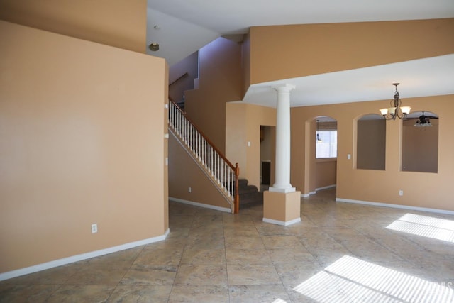 unfurnished living room featuring stairway, baseboards, high vaulted ceiling, and ornate columns