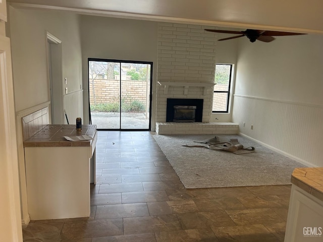 unfurnished living room with a fireplace and ceiling fan