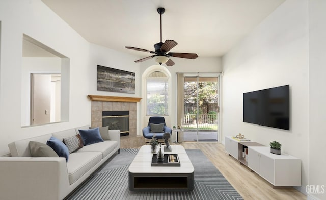 living room featuring a fireplace, light wood finished floors, and ceiling fan