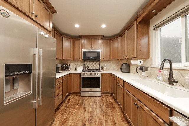 kitchen featuring tasteful backsplash, sink, appliances with stainless steel finishes, and light hardwood / wood-style flooring