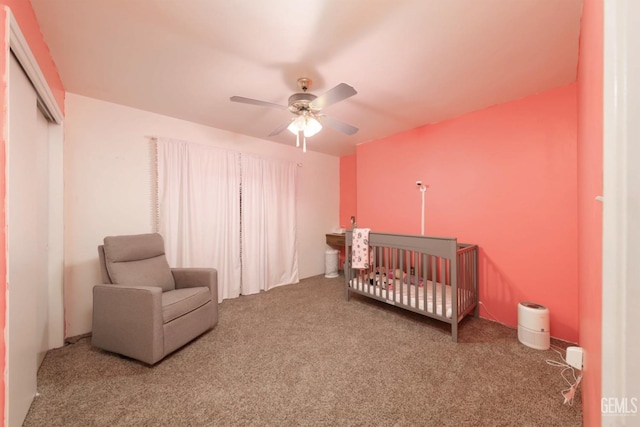 carpeted bedroom with a closet, a nursery area, and ceiling fan