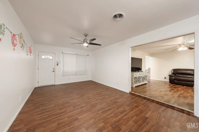 unfurnished living room with ceiling fan and dark wood-type flooring