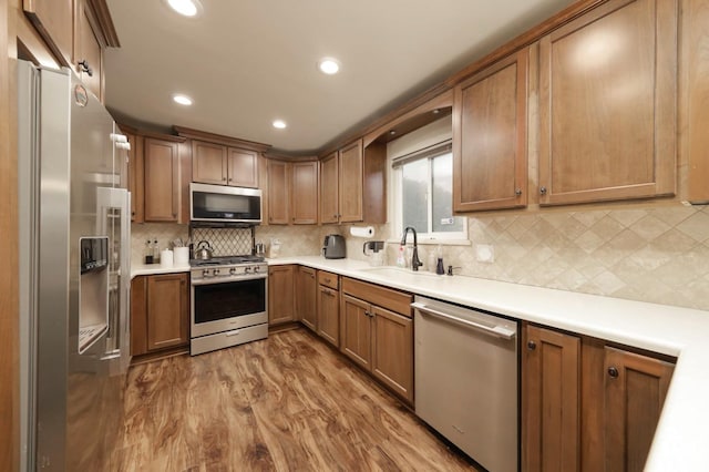 kitchen featuring tasteful backsplash, stainless steel appliances, hardwood / wood-style flooring, and sink