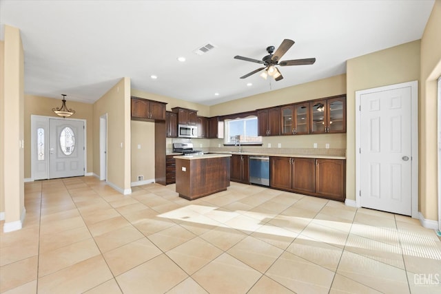 kitchen featuring pendant lighting, light tile patterned flooring, ceiling fan, appliances with stainless steel finishes, and a kitchen island