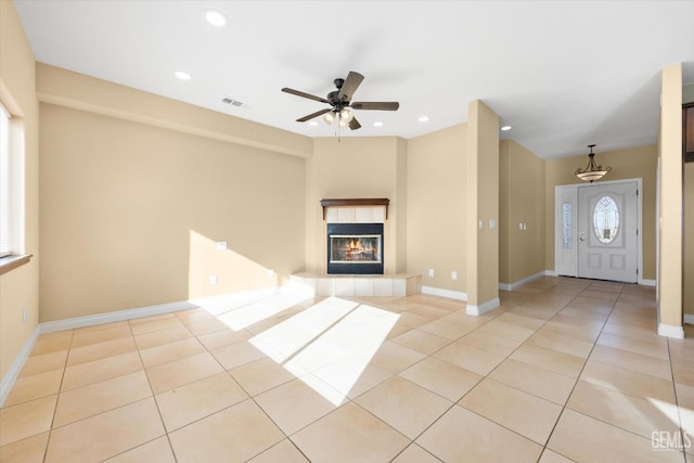 unfurnished living room with light tile patterned floors, ceiling fan, and a tiled fireplace