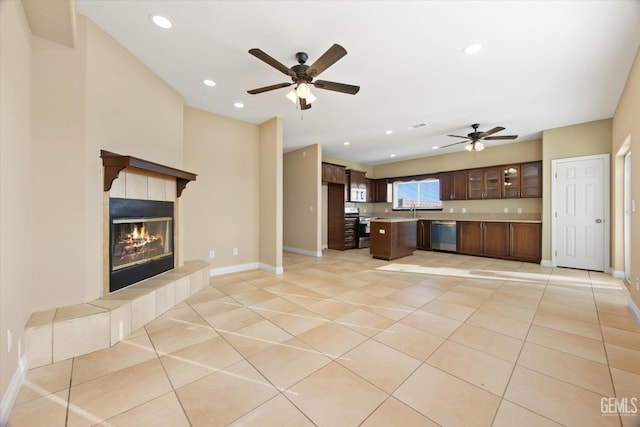 unfurnished living room featuring ceiling fan, a fireplace, light tile patterned floors, and sink