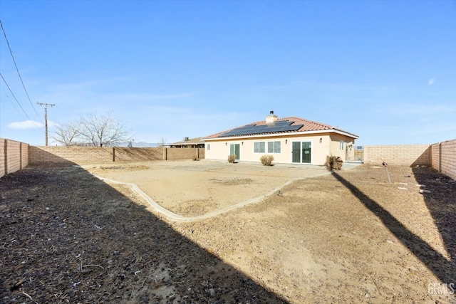 rear view of property featuring solar panels