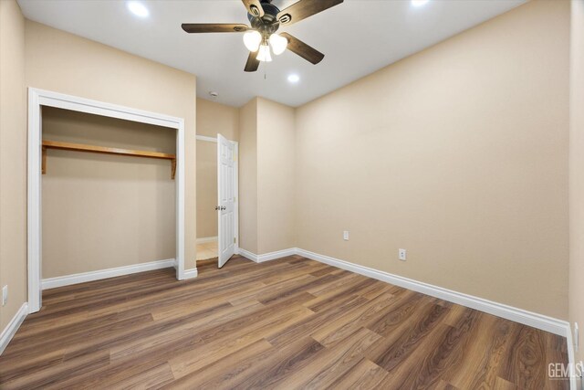 unfurnished bedroom with ceiling fan, a closet, and dark wood-type flooring