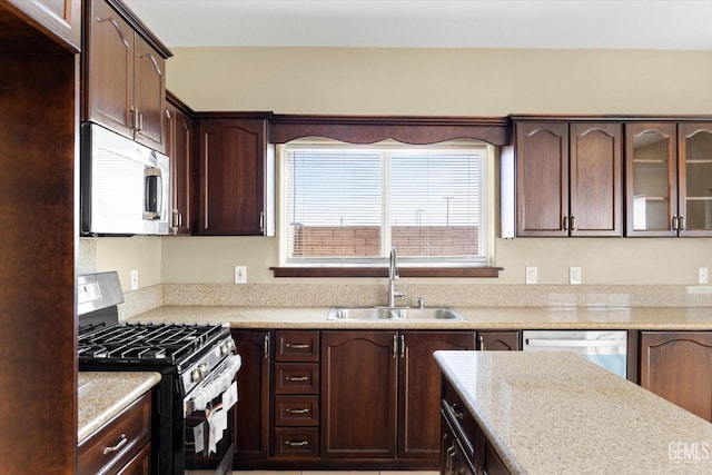 kitchen featuring light stone countertops, sink, stainless steel appliances, and dark brown cabinets