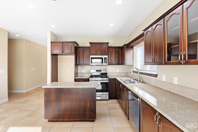 kitchen with light stone countertops, appliances with stainless steel finishes, sink, a center island, and light tile patterned flooring