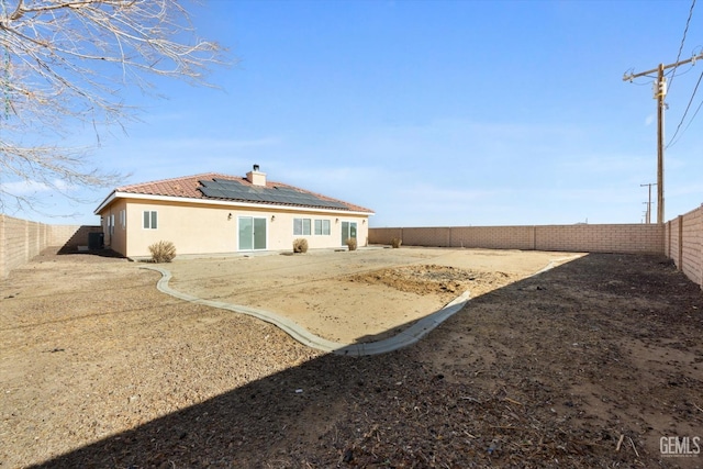 back of house featuring solar panels