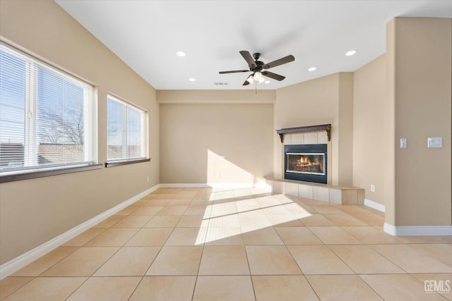 unfurnished living room featuring a tiled fireplace, ceiling fan, and light tile patterned floors