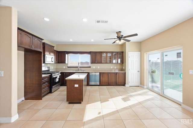 kitchen with stainless steel appliances, ceiling fan, sink, a center island, and light tile patterned flooring