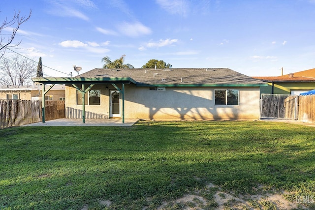 rear view of house with a lawn, a patio, a gate, fence, and stucco siding