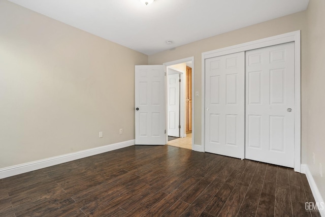 unfurnished bedroom featuring a closet, baseboards, and wood finished floors