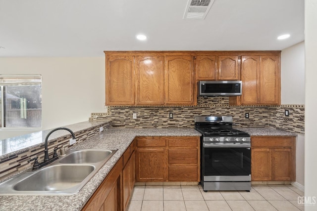 kitchen with appliances with stainless steel finishes, brown cabinets, visible vents, and a sink