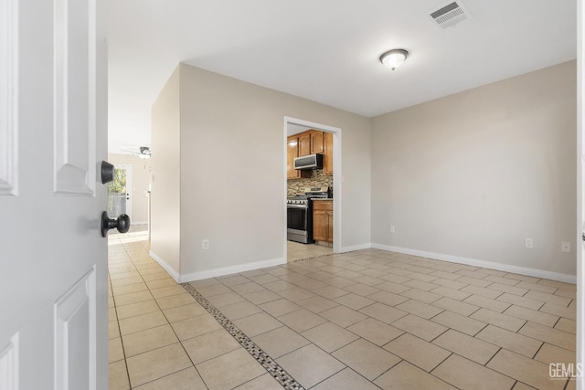 spare room featuring light tile patterned floors, ceiling fan, visible vents, and baseboards