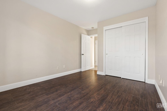 unfurnished bedroom featuring baseboards, dark wood finished floors, and a closet