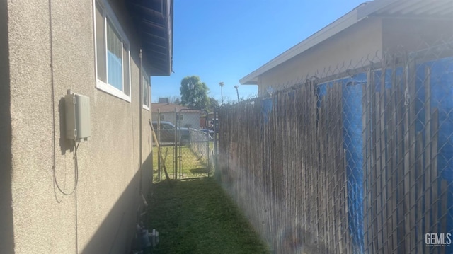 view of side of home with a gate and stucco siding