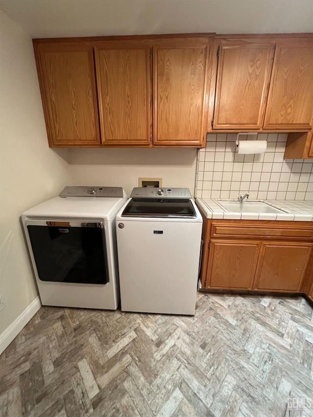 washroom with cabinet space, baseboards, separate washer and dryer, and a sink