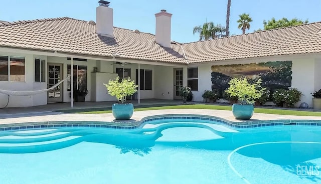 back of property with a tile roof, a patio area, a chimney, stucco siding, and ceiling fan